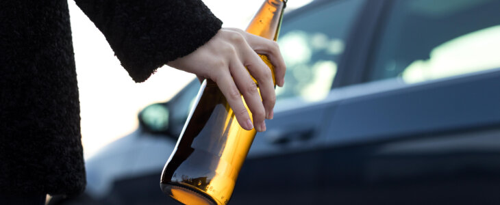 Young adult drinking beer while driving, she is going to a party.