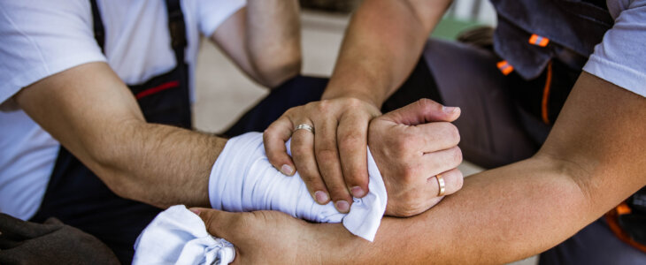 Close up of unrecognizable worker helping his colleague who injured hand at work.