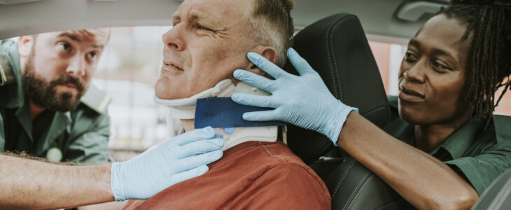 Paramedic placing a cervical collar to an injured man from car accident